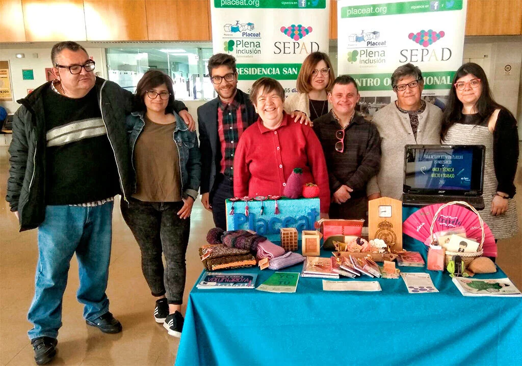 Foto de Familia de usuarios, voluntarios y profesionales de la Asociación PLACEAT en su stand de la I Feria de Voluntariado de la Universidad de Extremadura